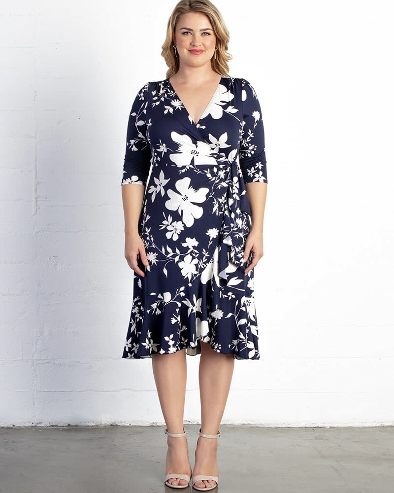 Front of a model wearing a size 0X Flirty Flounce Wrap Dress in NAVY FLORAL PRINT by Kiyonna. | dia_product_style_image_id:228767